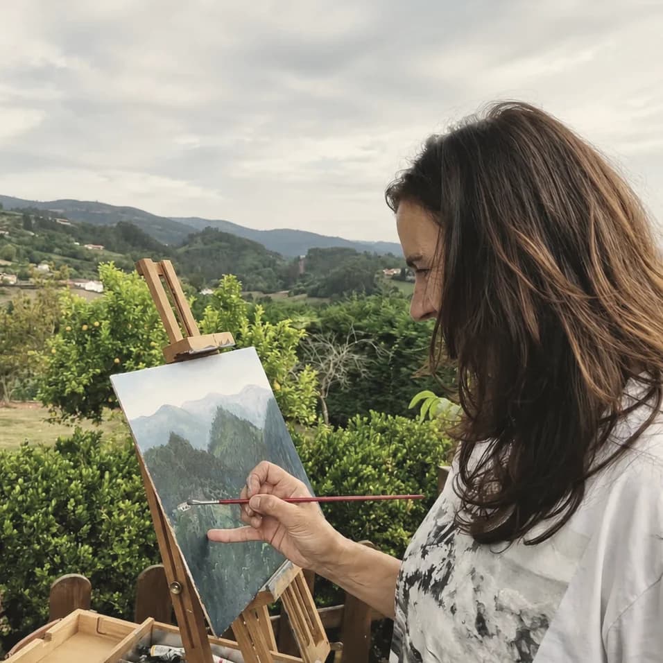 Tere Casielles pintando al óleo al aire libre, frente a un valle asturiano