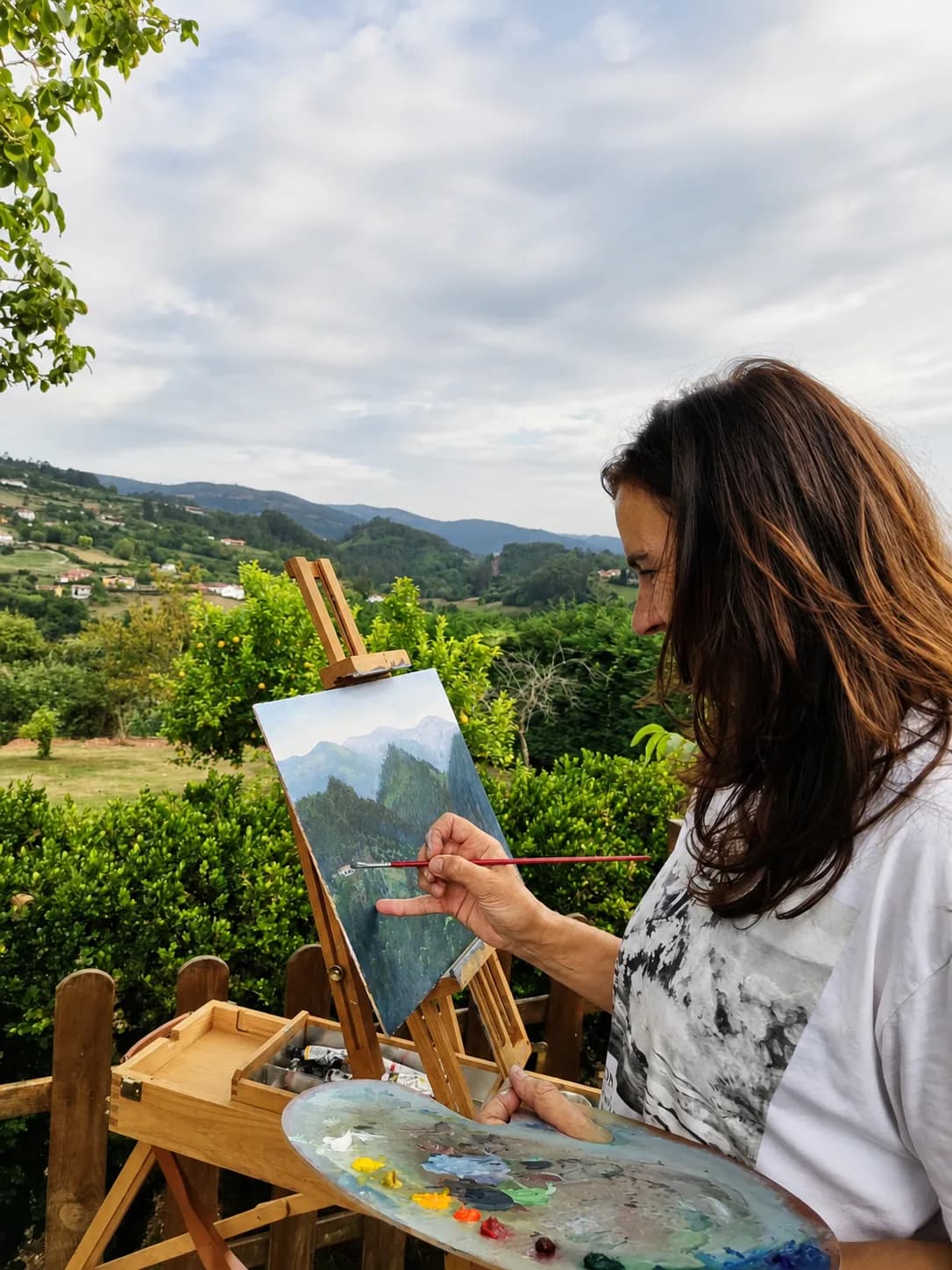 Tere Casielles pintando al óleo al aire libre, frente a un valle asturiano